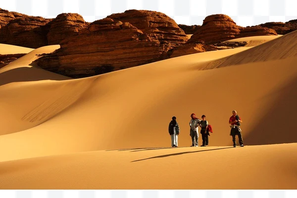Personas en dunas de arena en un desierto rocoso