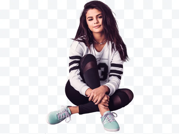 Selena Gomez sentada con ropa deportiva blanca y negra y zapatillas verdes.